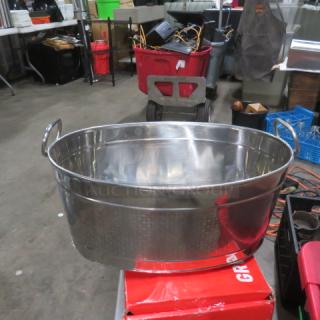 Stainless steel beverage tub with dual handles, polished finish, excellent condition, on display in a warehouse setting.