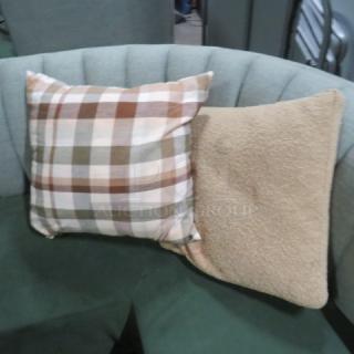 Assorted pillows on a green sofa; one with a plaid pattern in brown and beige tones, the other in solid beige.