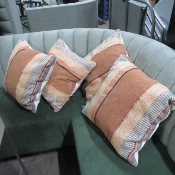 Assorted pillows, set of four, with striped design in earthy tones. Excellent condition on green tufted sofa.