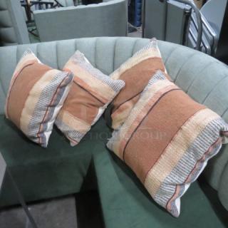 Assorted pillows, set of four, with striped design in earthy tones. Excellent condition on green tufted sofa.