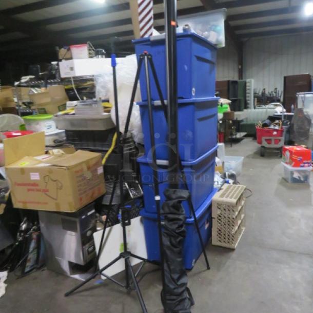 Projector screen with two tripods in warehouse, good condition. No visible tags or labels.