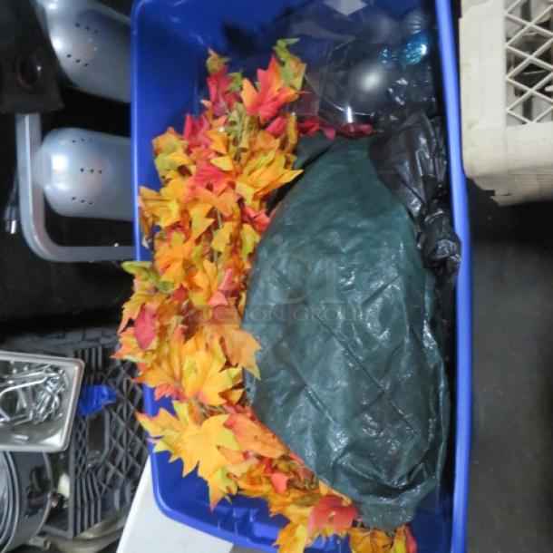 Blue storage bin containing autumn leaves decor and other mixed items. Appears in used condition, ideal for seasonal decoration.