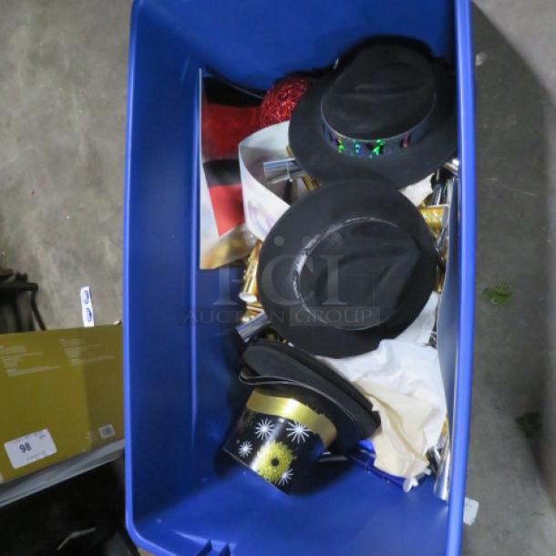 Blue bin filled with assorted decor items including black hats with bands and a gold and black top hat.