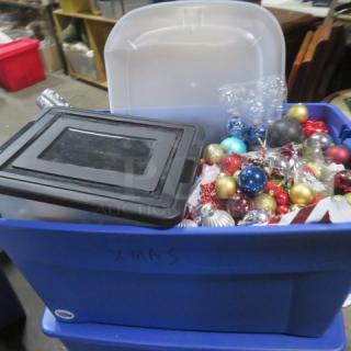 Blue storage bins filled with assorted holiday decor items, including colorful ornaments.