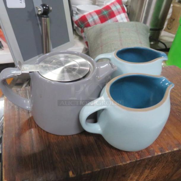Assorted creamer set; includes two light blue creamers and one gray teapot with metal lid. Excellent condition, ceramic.