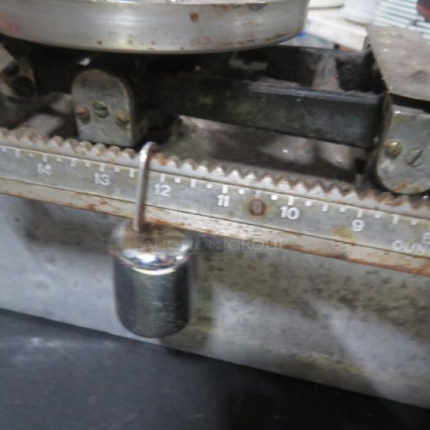 Vintage baker's scale with metal weight, rusted finish, visible calibration markings; shows signs of age and use.
