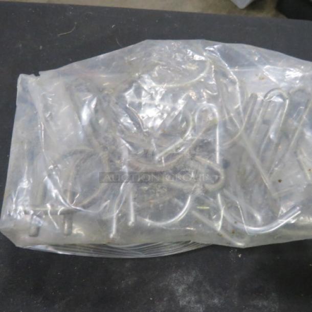 Clear plastic bag containing a lot of metal pot hooks. Hooks appear new, unopened, and various in shape and size.