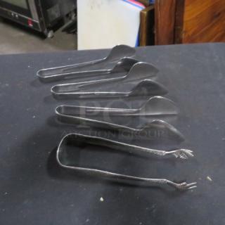 Assorted stainless steel tongs, five pieces, various sizes, in good condition, suitable for serving or kitchen use.