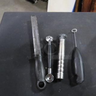 Assorted bar utensils including a zester, melon baller, muddler, and milk frother, in used condition.