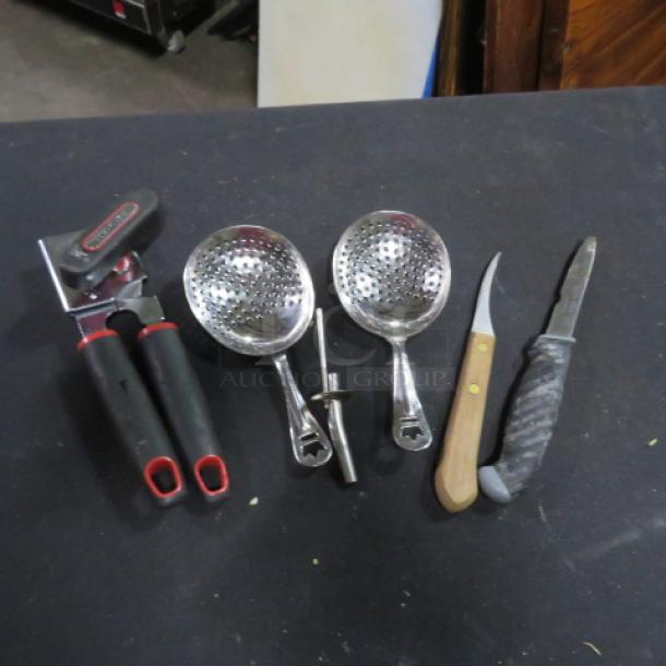 Assorted kitchen utensils, including a manual can opener, two slotted ladles, and two knives with wood and textured grips.