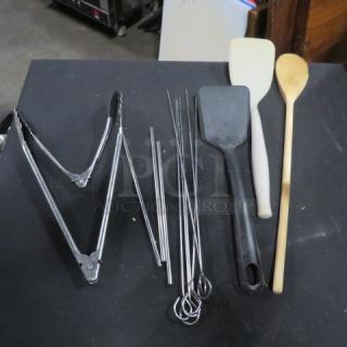 Assorted lot of kitchen utensils including tongs, skewers, spatulas, and a wooden spoon. Mixed materials, good condition.