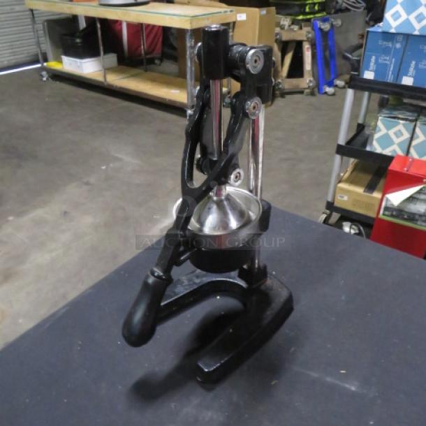 Commercial juicer with black metal base, sturdy handle, and stainless steel press. Good condition, ideal for heavy-duty use.