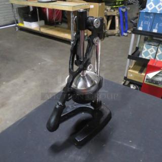 Commercial juicer with black metal base, sturdy handle, and stainless steel press. Good condition, ideal for heavy-duty use.