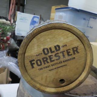 Wooden whiskey barrel with "Old Forester" logo, featuring wooden staves and metal hoops. Used condition.