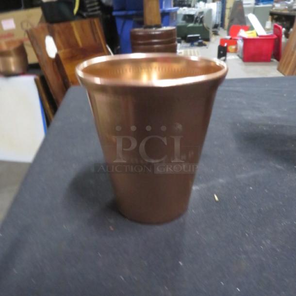 Copper mule cup branded Woodford Reserve, cylindrical shape, polished finish, good condition, engraved logo visible.