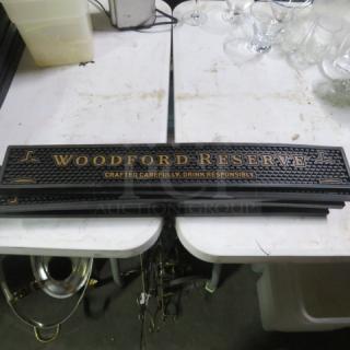 Woodford Reserve bar mat with gold lettering, reads "Crafted Carefully, Drink Responsibly." Black, textured surface. Good condition.
