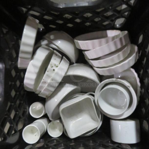 A collection of white dishware including bowls, plates, and cups, stacked in a crate. Item condition is used.