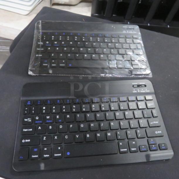 Wireless Keyboard 2XBID, black, compact design, two units. One sealed, new condition, featuring blue function keys.