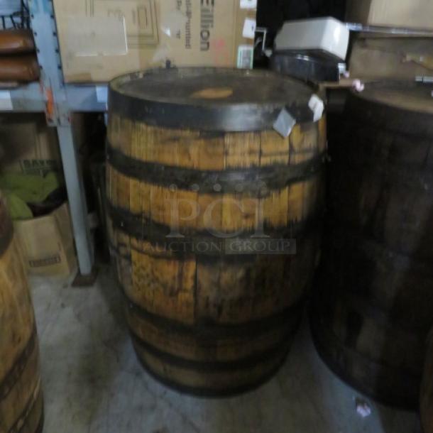 Jack Daniels wooden barrel stamped "Jack Daniels Operation Ride Home" on top, showing wear, in storage setting.