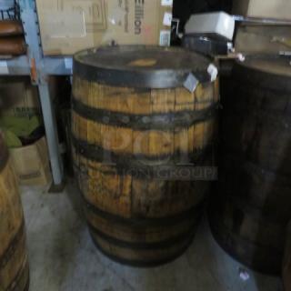 Jack Daniels wooden barrel stamped "Jack Daniels Operation Ride Home" on top, showing wear, in storage setting.