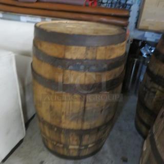 Wooden whiskey barrel with metal hoops, rustic appearance. Good condition, suitable for storage or decorative use.