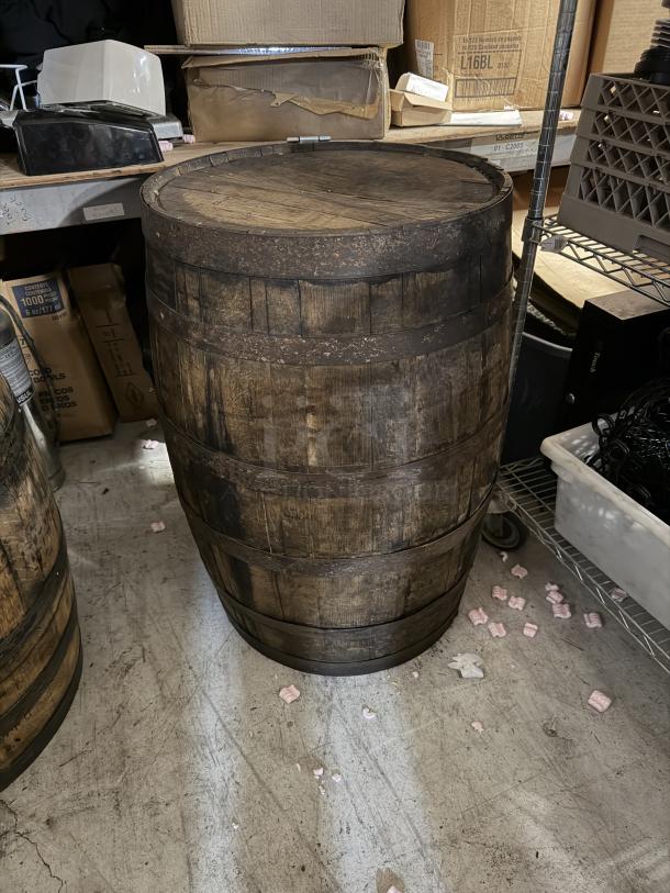 Wooden whiskey barrel, rustic and aged appearance, visible metal bands, suitable for decor or display. Some wear.