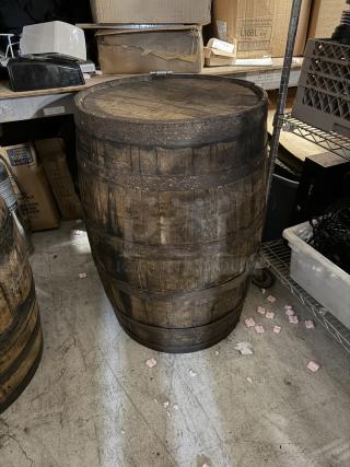 Wooden whiskey barrel, rustic and aged appearance, visible metal bands, suitable for decor or display. Some wear.