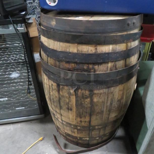 Wooden whiskey barrel with Jack Daniels stamp on top. Features metal bands, natural wood finish, and shows moderate wear.