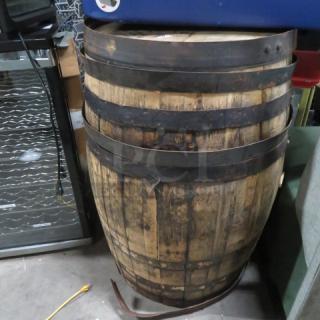 Wooden whiskey barrel with Jack Daniels stamp on top. Features metal bands, natural wood finish, and shows moderate wear.