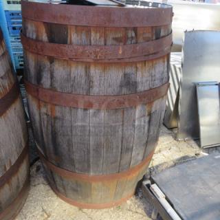 Antique wooden whiskey barrel with metal bands, weathered finish, standing upright. Ideal for decor or collection.