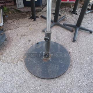 Black metal umbrella base, round design, visible scuffs, smooth finish, outdoor use, suitable for stability.