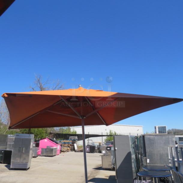 Extra-large orange Sunbrella with sturdy metal pole; outdoor setting, excellent condition, ideal for ample shade.