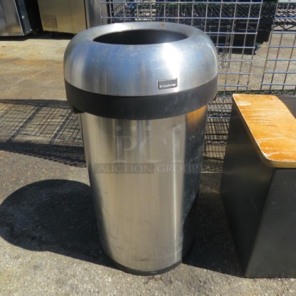 Simple Human round trash can with lid, stainless steel, noticeable wear, brand label visible, outdoor setting.