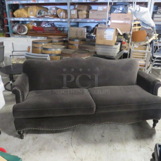 Brown velvet cushioned couch, 80x35x35, features curved back, nailhead trim, and wooden legs. Good condition.