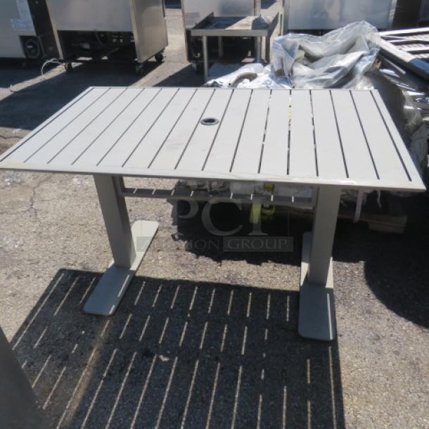 Modern outdoor patio table, 50x31x30 inches, gray slatted design, central umbrella hole, sturdy metal legs.