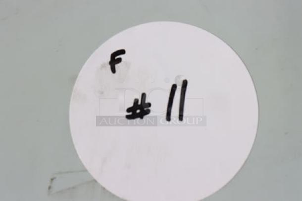 White circle tag with black marker text "F #11" on surface; no other notable features visible.