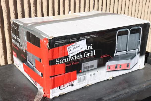 Brand new Avantco PG400 Commercial Panini Grill with grooved plates in original damaged packaging. Model PG400, 19 5/8" x 9 1/8" cooking surface, 120V, 3500W.
