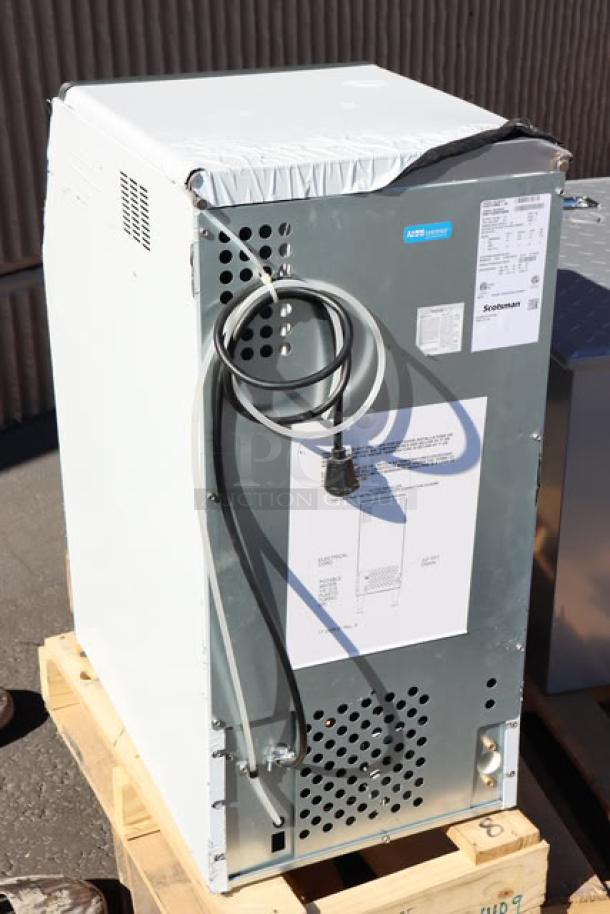 BRAND NEW Scotsman CU0715MA-1 15" ice machine, air-cooled, 80 lb capacity, 115v. Dent on back corner, visible labels and power cable.