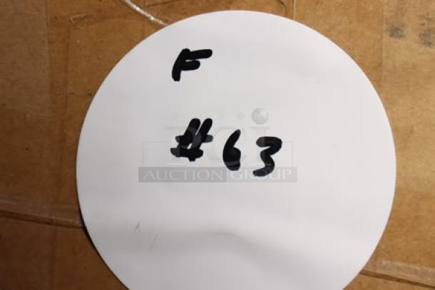 Alt text: White circular label with handwritten text "F #63" on a cardboard background.