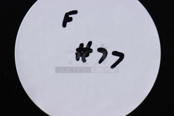 Alt text: White circle label with handwritten text “F #77” on a black background.