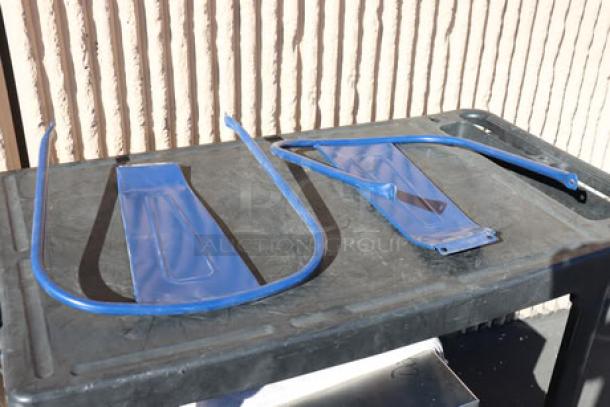 Two blue metal barstool parts, possibly legs and seat support, displayed on a black table.