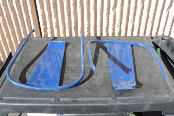 Blue metal chair frames on a black surface, partially assembled, showing bolt holes and curved design.