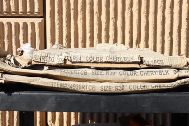 Cardboard packaging for Lancaster Table & Seating 30" laminated round table top, marked "COLOR: CHERRY/BLK," revealing damaged packaging.