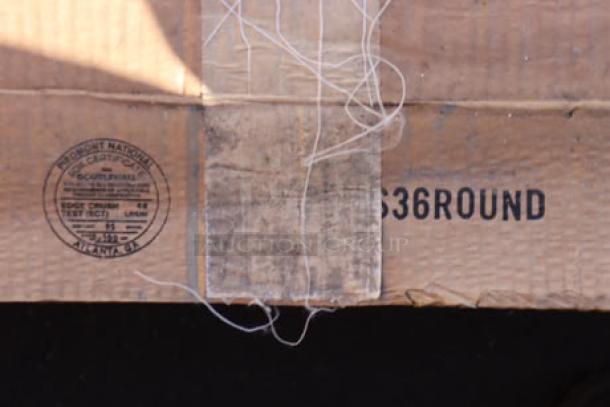 Cardboard packaging showing industrial stamp and "36 ROUND" label, indicating a 36" round table top. Box shows signs of wear.