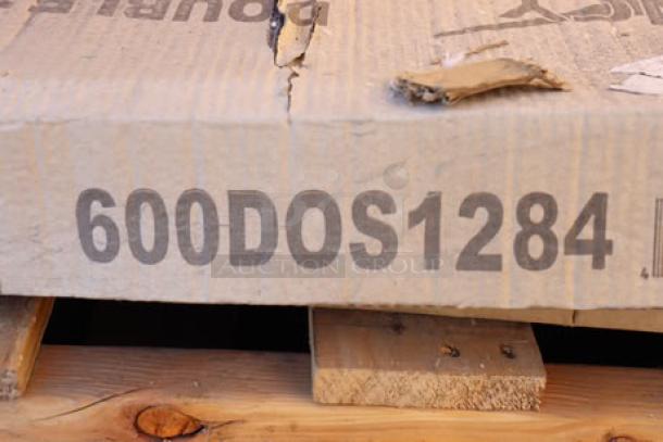 A damaged cardboard box stamped with "600DOS1284" sits on a wooden pallet containing mixed auction items.