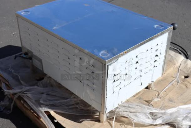 Mixed lot of equipment including a stainless steel countertop appliance on a wooden pallet. Visible dents and surface marks.