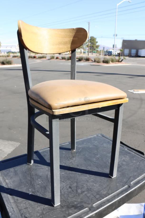 New Lancaster Table & Seating Boomerang Chair with padded vinyl seat, wooden backrest, and metal legs, outdoor setting.