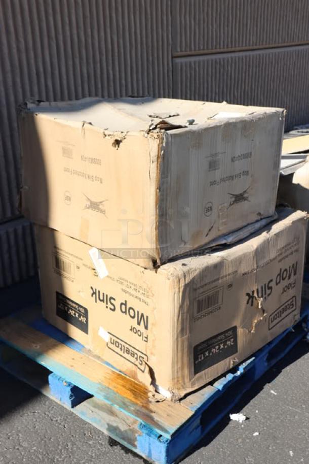 Damaged boxes on a blue pallet labeled "Steelton", containing a mop sink. Visible wear indicates possible scratches or dents.