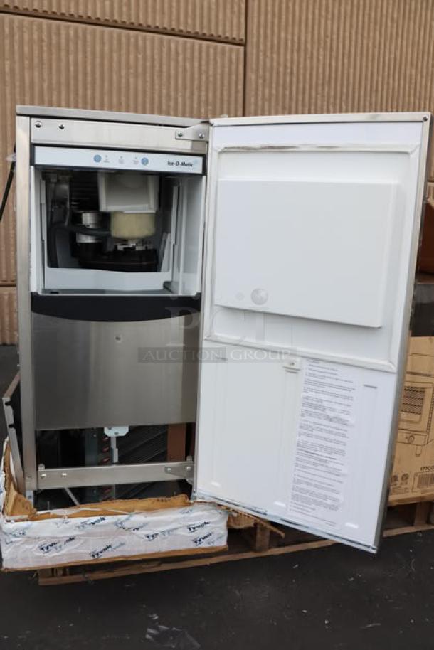Brand new Ice-O-Matic GEMU090 air-cooled undercounter ice machine, serial 24701321015747, with open door showing interior.