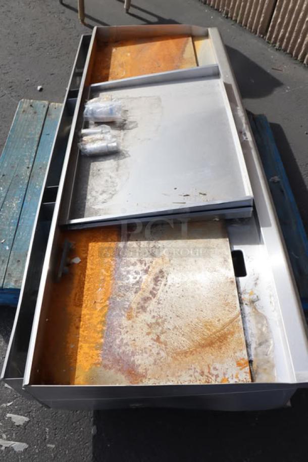 Brushed metal industrial equipment on a wooden pallet. Surface shows clear signs of wear and rust.